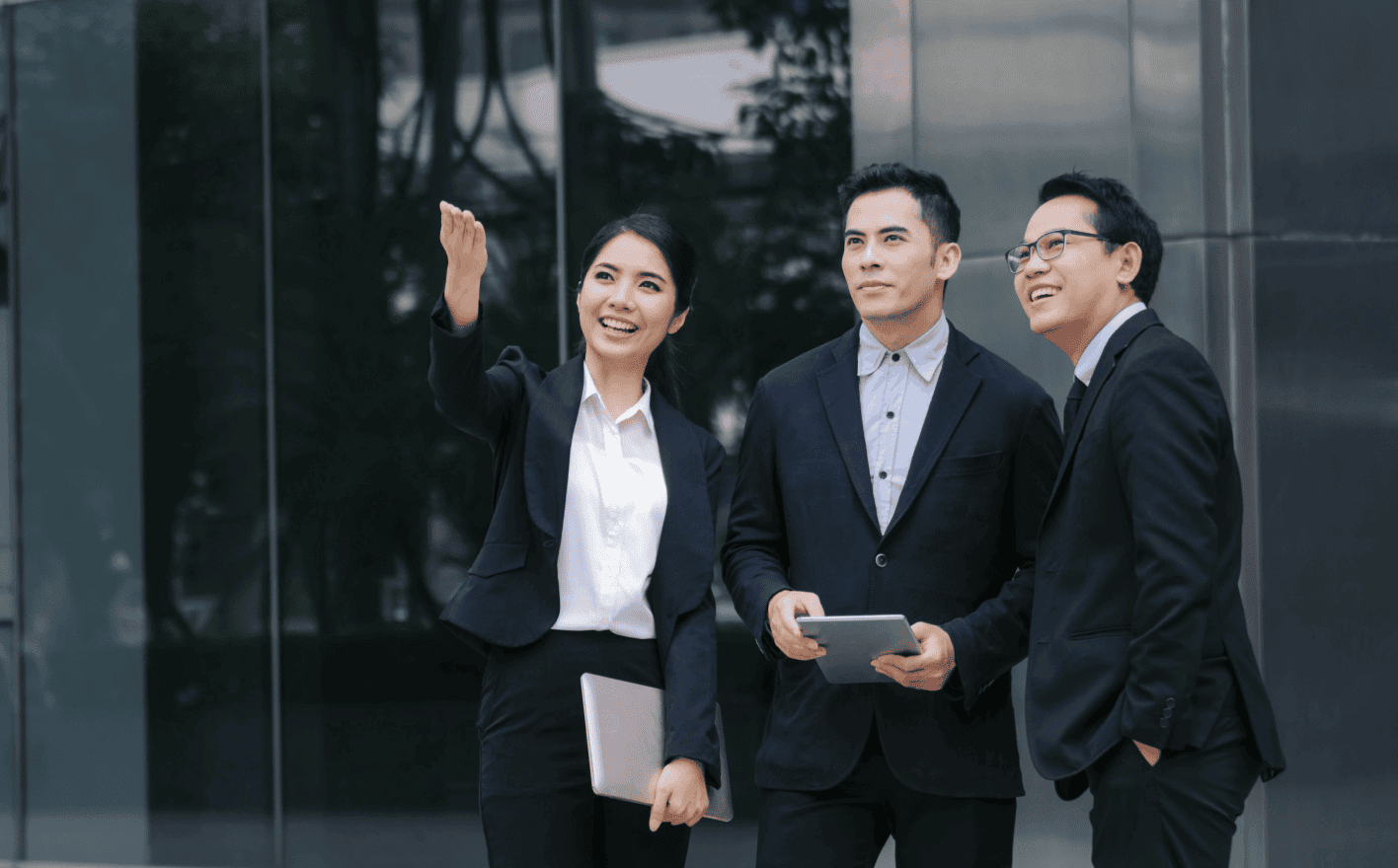 A group of Asian business professionals engaged in discussion around a conference table.